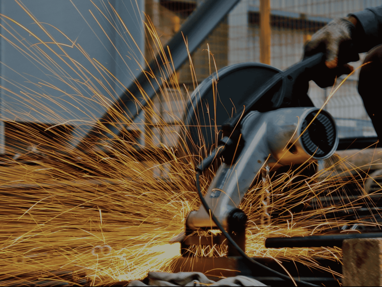 Close-up of a welder’s gloved hand at work, sparks flying from heavy machinery, representing industrial SME activity.